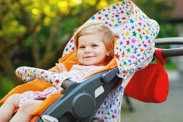 在婴儿车或婴儿车里坐着一个可爱的 带着微笑的小女孩的画像 然后去散步 快乐可爱的孩子在户外玩的开心 健康的女儿 — 图库照片