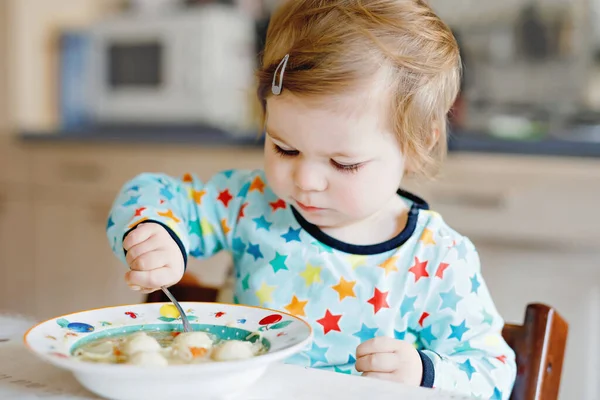 スプーン野菜の麺スープから食べる愛らしい赤ちゃんの女の子 給餌と開発の概念です かわいい幼児 スプーンが高い椅子に座って自分で食べることを学ぶ娘 — ストック写真