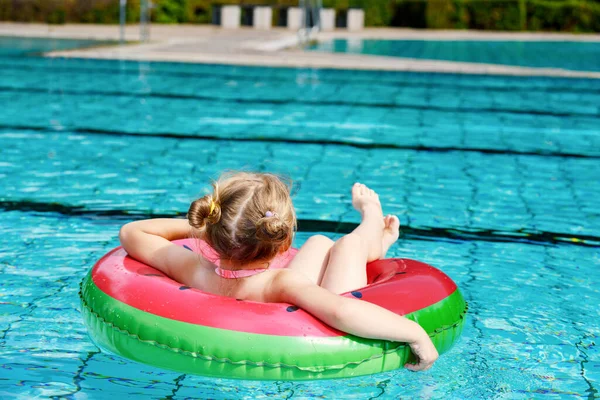 阳光明媚的夏日 一个快乐的小女孩在室外游泳池里玩着五彩缤纷的充气环 学龄前儿童学习游泳 夏季户外活动 — 图库照片
