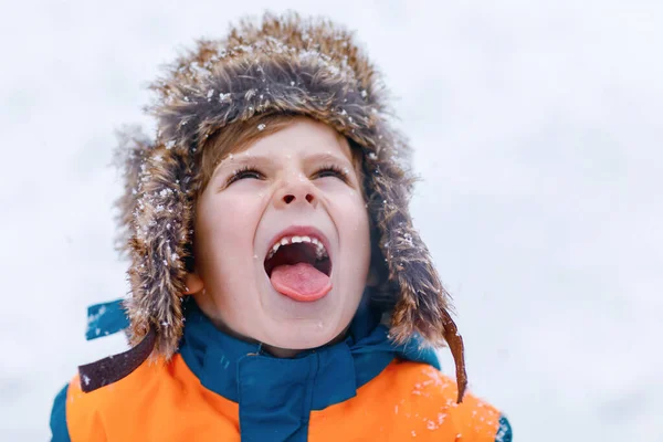 雪の中屋外で遊んでカラフルな服を着た面白い小さな学校の少年 寒い雪の日には冬の子供たちと積極的なレジャー 雪と遊んで楽しい子供 — ストック写真