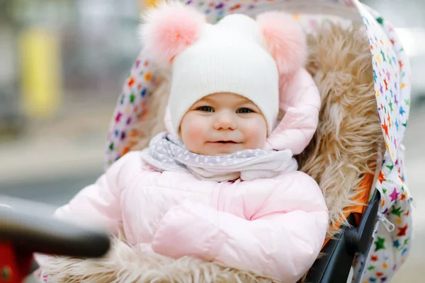 可爱的小女孩在寒冷的秋天 冬天或春天坐在婴儿车或婴儿车里 快乐的孩子 穿着温暖的衣服 时髦的婴儿外套和帽子 雪花飘落 — 图库照片