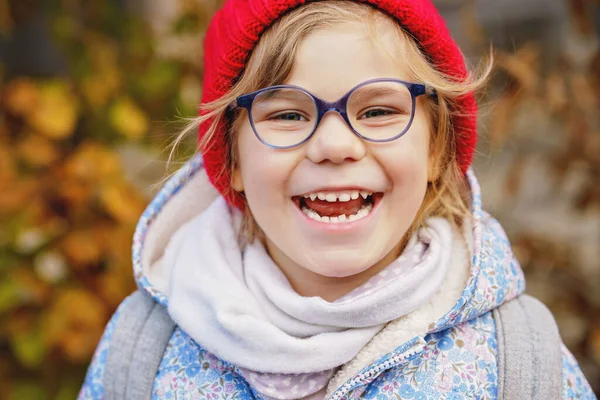 一个戴着眼镜 戴着红色帽子的可爱学龄前女孩的画像 快乐有趣的孩子戴着新的蓝色眼镜 秋天的城市日 — 图库照片