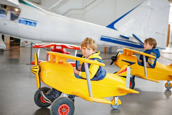 两个小男孩开着老式的大玩具踏板飞机 在屋里玩得很开心 学校放假期间与子女一起积极休闲活动 — 图库照片