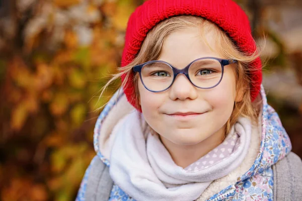 一个戴着眼镜 戴着红色帽子的可爱学龄前女孩的画像 快乐有趣的孩子戴着新的蓝色眼镜 秋天的城市日 — 图库照片