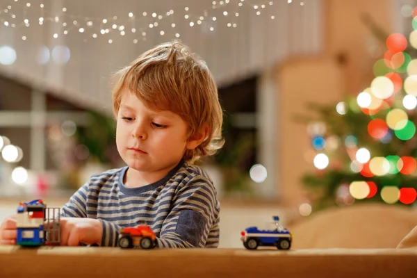 금발의 집에서 자동차와 장난감을 가지고 재미있게 좋아한다 크리스마스 배경에 — 스톡 사진