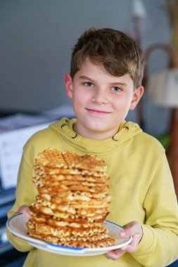 Elinde taze waffle tutan mutlu okul çocuğunun portresi. Tatlı bisküvi ekmeğiyle gülümseyen aç çocuk. Tatlı Belçika waffle 'ları