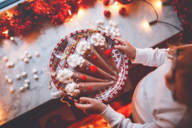 Çikolata kakao tozu ve marşmelovdan yapılmış ren geyiği tutan küçük anaokulu kızı. Noel 'de çocuklar için kendi yaptığım tatlı içeceği.