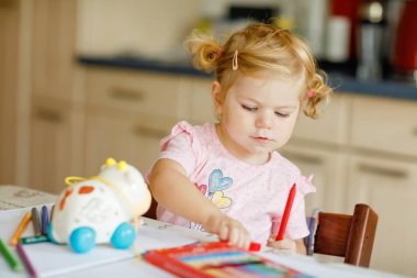 Kalemle resim yapmayı öğrenen sevimli bir bebek. Küçük çocuk renkli keçeli kalemlerle evde resim çiziyor. Evde ya da çocuk odasında renkler deneyen sağlıklı, mutlu bir kız.