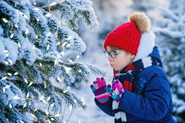 Small girl playing with snow. Happy preschool child in winter forest on snowy cold december day