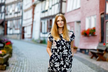 Yazlık elbiseli, uzun saçlı güzel bir kadın Alman şehrinde yürüyüşe çıkıyor. Mutlu kız Almanya 'da eski evleri olan küçük şirin bir Fachwerk kasabasında yürüyor.