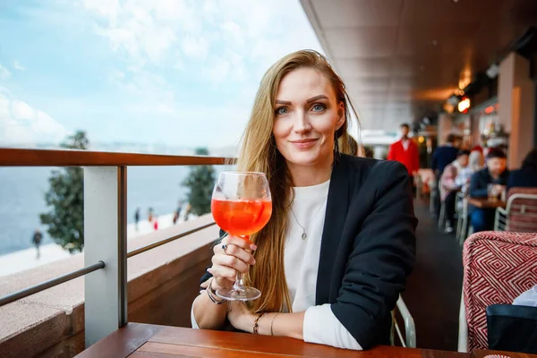 若いビジネスマンの女性がアルコールカクテルを飲んでいる 晴れた夏の日には屋外カフェやレストランで一人で幸せな女性 会議の間に昼食のための休憩 — ストック写真