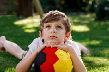 Aktif çocuk mutlu çocuk futbol topu Alman bayrağı renklerde oynamak. Sağlıklı çocuk futbol oyunu ve eylem açık havada ile eğleniyor.