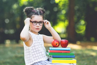 Okul veya kreş ilk günü kitap ve holding farklı renkli kitap, elma ve gözlük okuma mutlu sevimli küçük çocuk kız. Geri okul kavramı. Sağlıklı çocuk İlköğretim sınıf