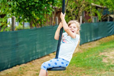 Mutlu kız teleferiğe biniyor dışarıda sallanıyor oyun parkında oyun ekipmanları çalıyor. Çocuk dışarıda eğleniyor. Anaokulu çocuğu yaz günü sallanıyor. Çocuklarla etkinlik