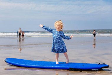 Ballybunion Sörfçü Plajı 'nda küçük şirin bir kız sörf tahtasında ilk kez eğleniyor, İrlanda' nın batı kıyısında. Mutlu çocuk ailesiyle İrlanda yazının tadını çıkarıyor.