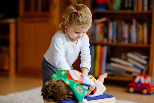 可愛いかわいい幼児の女の子は人形で遊んでいます 家庭や保育園で母親を演じる ロールゲームで楽しんでいる幸せな健康な赤ちゃん 現役娘とともにおもちゃ — ストック写真