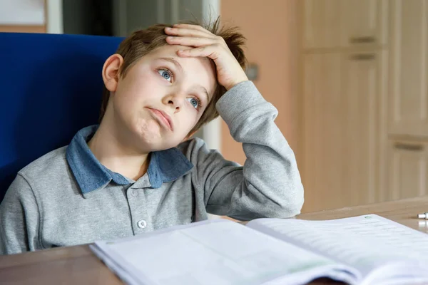 Upset school kid boy making homework during quarantine time from corona pandemic disease. Crying and sad boy frustrating staying at home