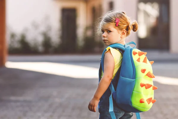 彼女の最初の日にかわいいかわいい幼児の女の子は学校に行く 健康な動揺悲しい赤ちゃんは保育園に歩いています 幼稚園への恐怖 街の通り 屋外でバックパックを持つ不幸な子供 — ストック写真