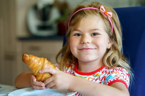 朝食で笑顔の子供 食べ物と幸せな子供たち 少女はクロワッサンを食べている 可愛いです就学前の女の子持っている健康的な食事 — ストック写真