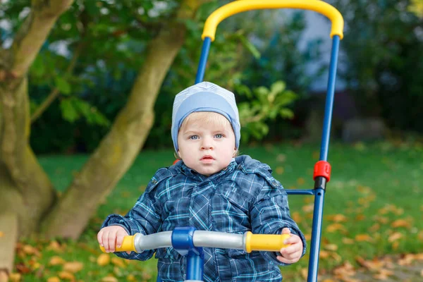 かわいい男の子が屋外で三輪車自転車で遊んでいます 秋の公園で幸せな子供の遊び 幼児の赤ん坊は流行のジャケットを身に着けている ブロンドの男の子の肖像画笑顔 秋のファッション 外のおしゃれな子供 — ストック写真