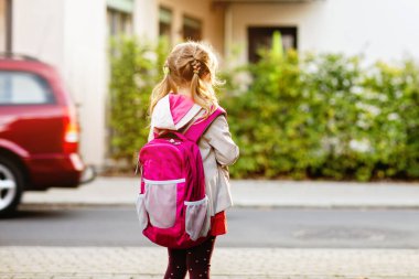 Anaokuluna giden tatlı küçük bir kız. Sağlıklı bir çocuk anaokuluna ve anaokuluna doğru yürüyor. Şehir caddesinde, açık havada sırt çantalı mutlu bir çocuk.
