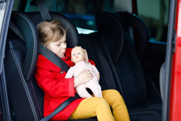 Mała Dziewczynka Siedząca Foteliku Samochodowym Trzymająca Ulubioną Zabawkę Dla Lalek — Zdjęcie stockowe
