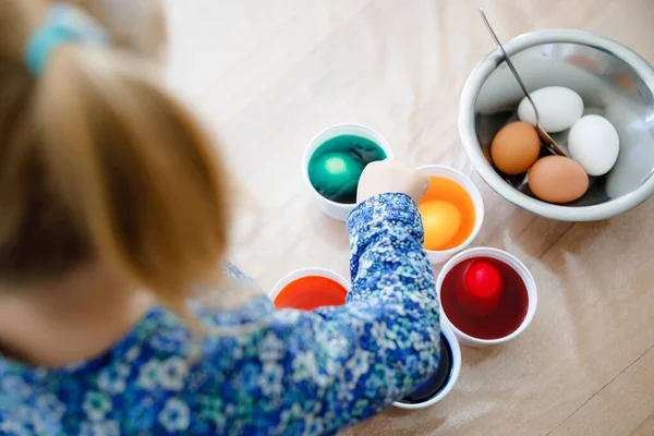 复活节彩蛋的小女孩的衣服 特写的孩子看上去很惊讶于彩色的鸡蛋 和家人一起庆祝节日 从上面看 不明不白的脸 — 图库照片