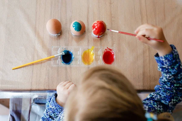 イースターのために卵を着色する小さな幼児の女の子の閉鎖 カラフルな色の卵を見て子供のクローズアップ 家族との休日を祝います 上から顔が見えない — ストック写真