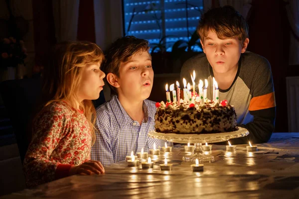 誕生日を祝う幸せな十代の男の子 就学前の妹の子供と2人の男の子の兄弟がケーキの上でろうそくを吹いています 幸せな家族の肖像画ともに3人の兄弟 — ストック写真