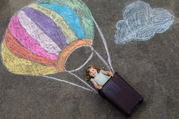快乐的小女孩坐着热气球飞行 粉刷着五彩缤纷的粉笔 粉刷着地面上的彩虹色或沥青色 可爱的孩子有乐趣 为孩子们提供创造性的闲暇 — 图库照片