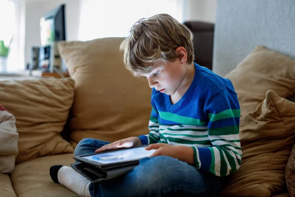 タブレットPcを持つ学校の少年 オンラインで学童学 家庭で学び 勉強し 遊ぶための電子機器 ラップトップPcを持つ小さな男の子 子供のためのガジェットと画面の時間 家で子供 — ストック写真