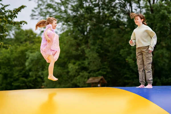 トランポリンでジャンプする小さな未就学児の女の子と学校の妹 幸せな面白い子供たち 夏に屋外活動で楽しい時間を過ごすことを愛する兄弟 ウクライナの旗色のトランポリン — ストック写真