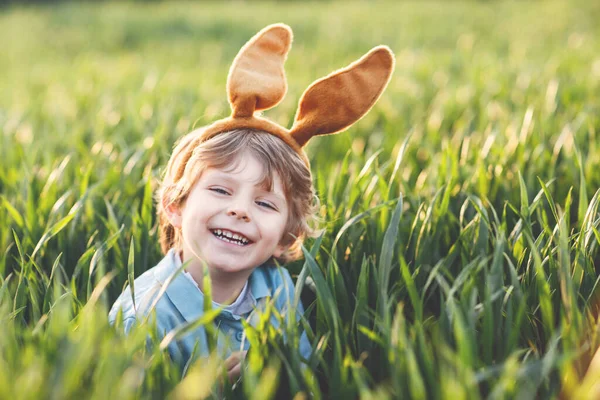可爱的小男孩 长着小兔子耳朵 在温暖的阳光明媚的天气里 在户外玩传统的复活节彩蛋猎杀游戏 庆祝复活节假期 毛毛虫发现 彩蛋在绿草中 — 图库照片