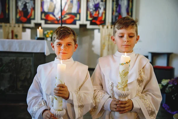 二人の小さな男の子は 彼の最初の聖なる交わりを受け取りました キリスト教のろうそくを持つ幸せな子供たち カトリックの呪いの伝統 祭壇の近くの教会の子供たち 白いガウンの兄弟 — ストック写真