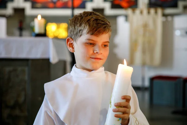 彼の最初の聖なる交わりを受けている小さな子供の男の子 キリスト教のろうそくを持つ幸せな子供 カトリックの呪いの伝統 祭壇の近くの教会で白い伝統的なガウンの子供 — ストック写真