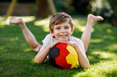 Aktif çocuk mutlu çocuk futbol topu Alman bayrağı renklerde oynamak. Sağlıklı çocuk futbol oyunu ve eylem açık havada ile eğleniyor.