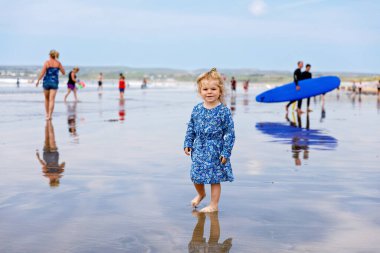 Little cute toddler girl at the Ballybunion surfer beach, having fun on with playing on west coast of Ireland. Happy child enjoying Irish summer and sunny day with family