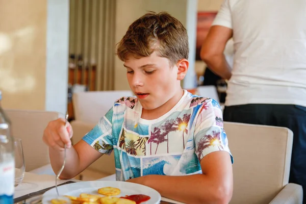 リゾートレストランで朝食をとる大人の少年 幸せな学校の子供は午前中に健康的な食べ物 卵を食べる — ストック写真