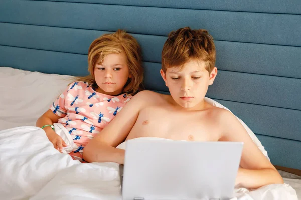 两个孩子 一个是小女孩 另一个是学童 在家里上网学习 孩子们 兄弟姐妹们用笔记本电脑进行家教和远程教育 兄妹玩笔记本玩得开心 — 图库照片