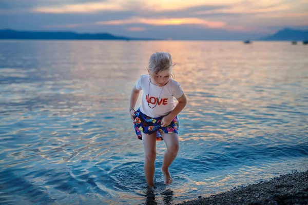 美しい海のビーチを歩く少女 海のビーチで日没までに幸せな就学前の子供の遊び 夏の子供連れの家族旅行 — ストック写真