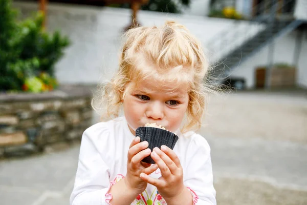 かわいい幼児の女の子は屋外カフェで甘い誕生日カップケーキを食べています 幸せな子供はマフィンを食べる — ストック写真