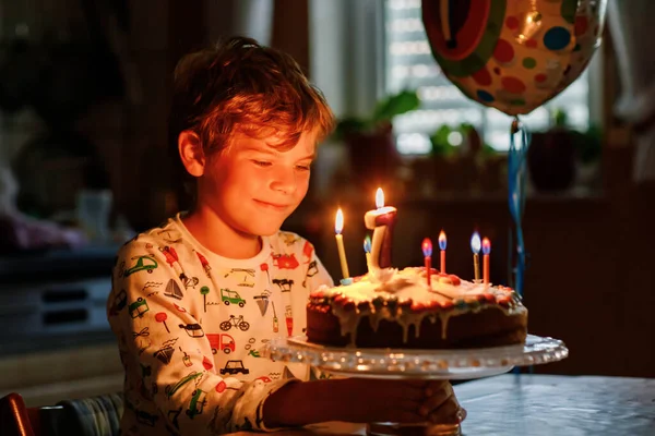 可爱的金发小男孩庆祝他的生日 小孩在自家做的烤蛋糕上吹了7支蜡烛 在室内 学生生日聚会 7周年家庭庆祝活动 — 图库照片