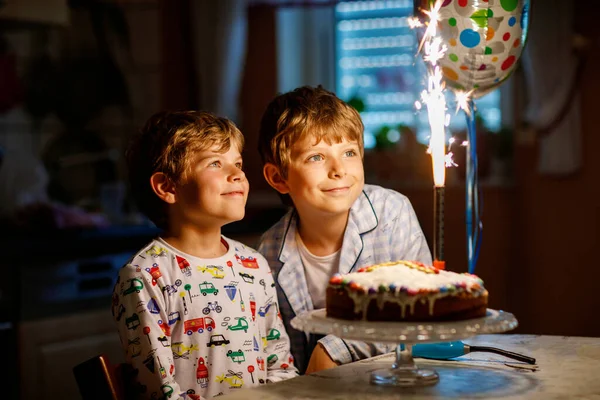 2人の美しい子供 誕生日を祝う小さな就学前の男の子 自家製の焼きケーキ 屋内でろうそくを吹いてください 兄弟姉妹の子供のための誕生日パーティー 幸せな双子についてギフトや花火上のタルト — ストック写真