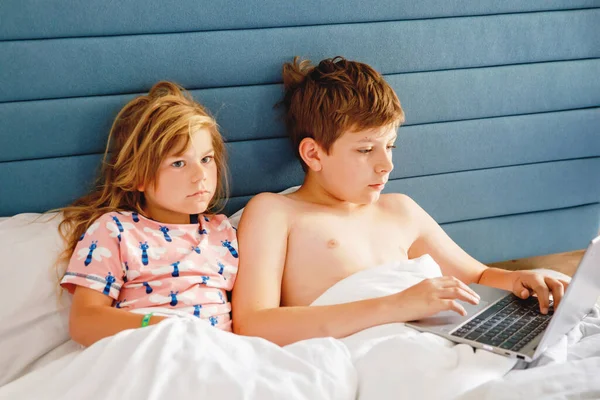两个孩子 一个是小女孩 另一个是学童 在家里上网学习 孩子们 兄弟姐妹们用笔记本电脑进行家教和远程教育 兄妹玩笔记本玩得开心 — 图库照片