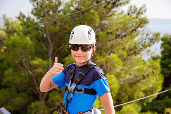 ジップラインアドベンチャーの準備をしている学校の少年 幸せな活動的な子供は頭部に安全ヘルメットを置いた 山に登る夏の楽しみ — ストック写真