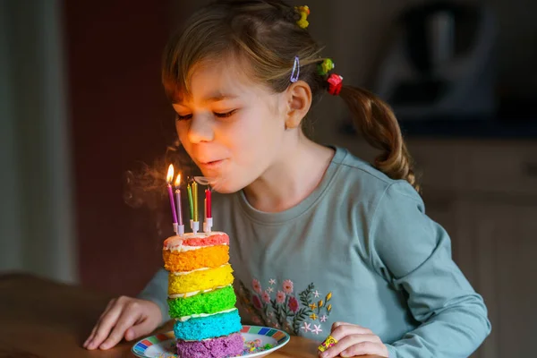 誕生日を祝う幸せな小さな就学前の女の子 手作りの虹のケーキ 屋内でかわいい笑顔の子供 幸せな健康な幼児吹いて6キャンドルオンケーキ — ストック写真