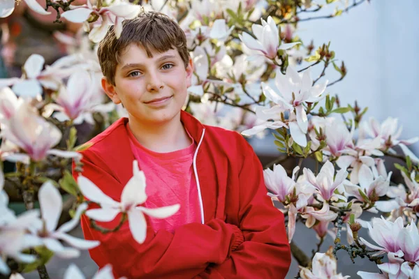 花のマグノリアの木の下に幸せなかわいい十代の男の子 10代の子供と春 — ストック写真