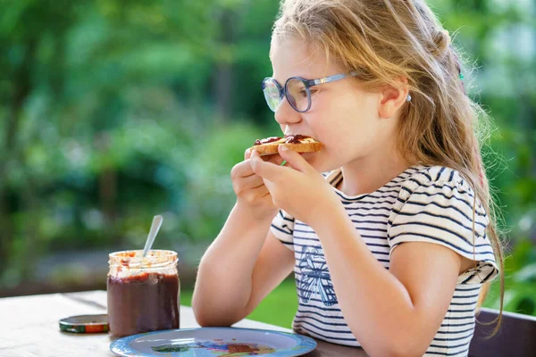 かわいい面白い就学前の女の子は朝食のために甘いパンを食べる 幸せな子供は イチゴ 桜や梅のジャムとパンロールを食べる 自家製ゼリーのある子供や子供のための健康食品 — ストック写真