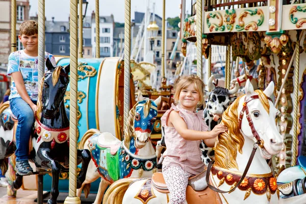 可敬的小女孩和小学生 乘坐着古老的旋转木马在法国的洪福勒市兜风 弟妹们 弟妹们玩得开心 — 图库照片