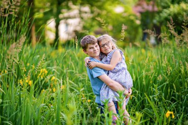 Okul çocuğu ve küçük kız kardeşi, anaokulu kızı parkta birlikte oynuyorlar. İki mutlu çocuk oyun oynuyor ve güneşli bir yaz günü eğleniyor. Birbirini seven kardeşler. Sevgili kız ve erkek kardeş.